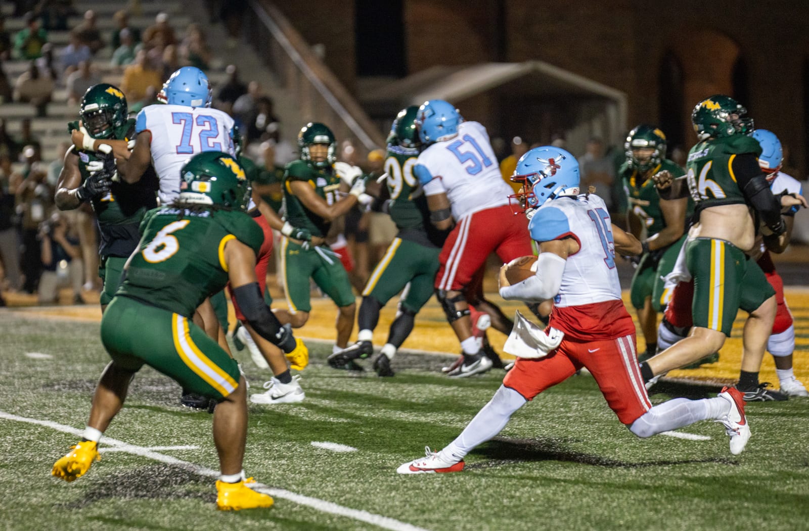 Delaware State quarterback Ui Ale tucks the ball and scrambles through traffic under the lights