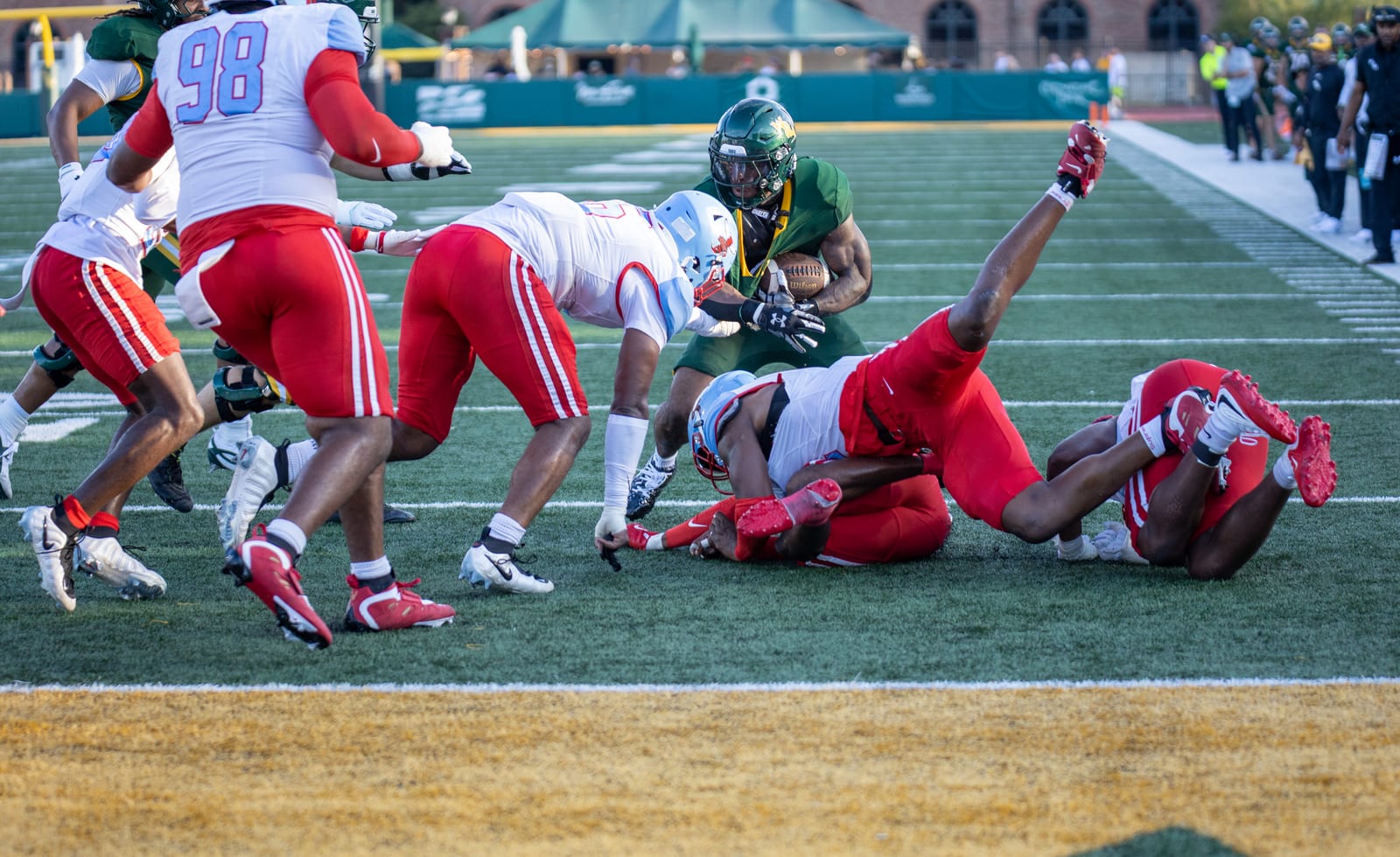 A William & Mary ballcarrier powers through a pile of fallen Delaware State defenders at the goal line