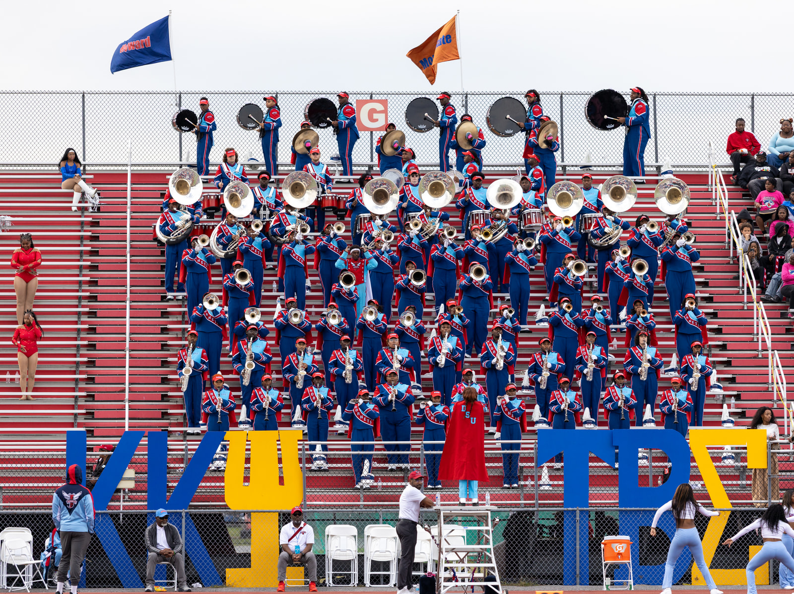 The Delaware State marching band performs from the stands above Greek letters set along the track